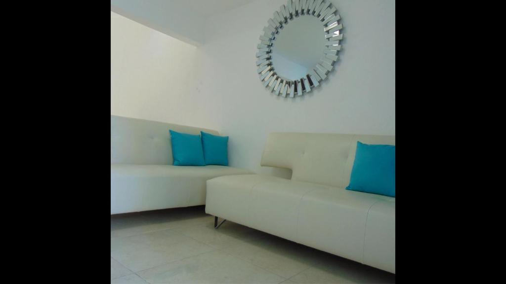 坎昆Departamentos Villas Capdeviel的白色沙发、蓝色枕头和镜子