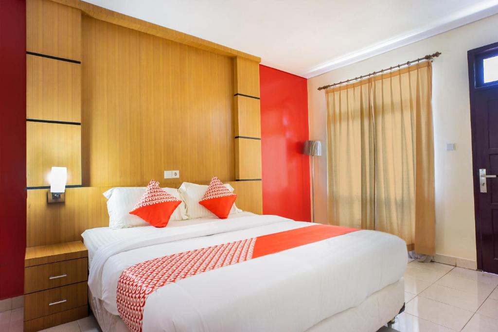 LhokseumaweOYO 1636 Wisma Kuta Karang的卧室配有红色色调的大型白色床