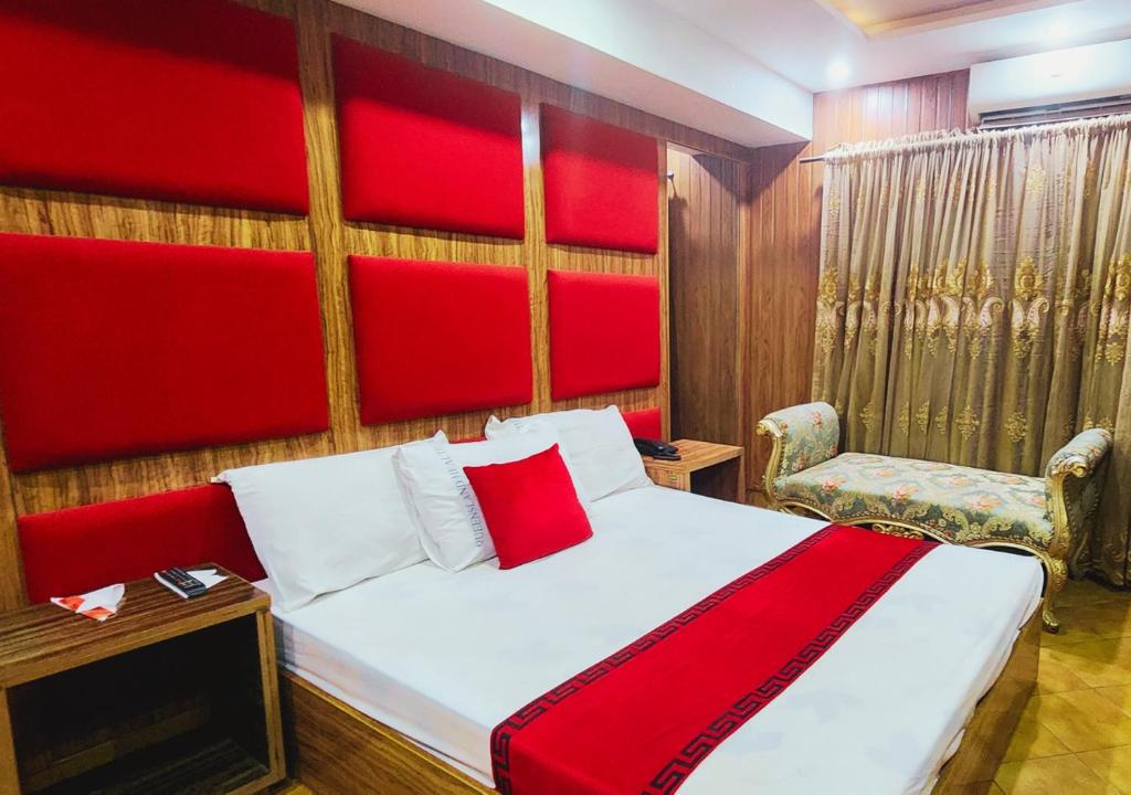 拉合尔Sapphire Inn Motel Lahore的一间卧室配有一张带红色床头板和椅子的床