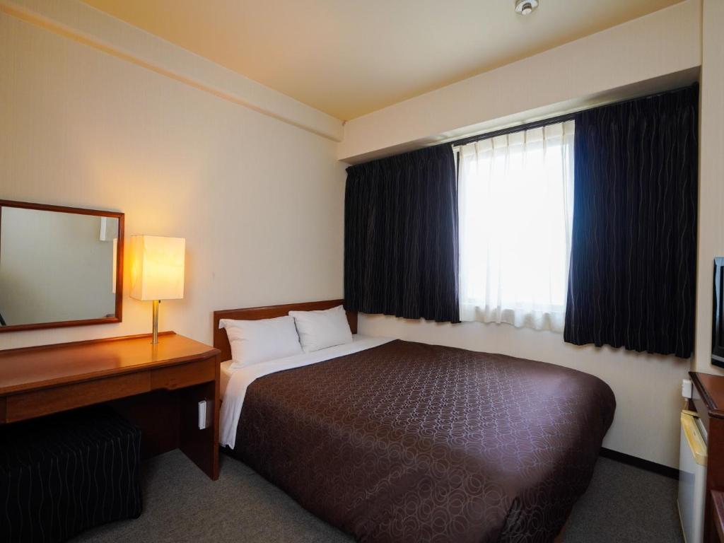 福冈Plaza Hotel Tenjin - Vacation STAY 40083v的酒店客房带一张床、一张书桌和一面镜子