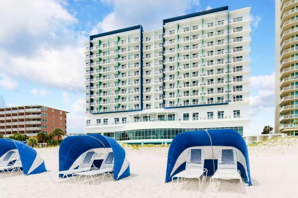 巴拿马城海滩Hyatt Place Panama City Beach - Beachfront的海滩上的酒店,配有椅子和帐篷