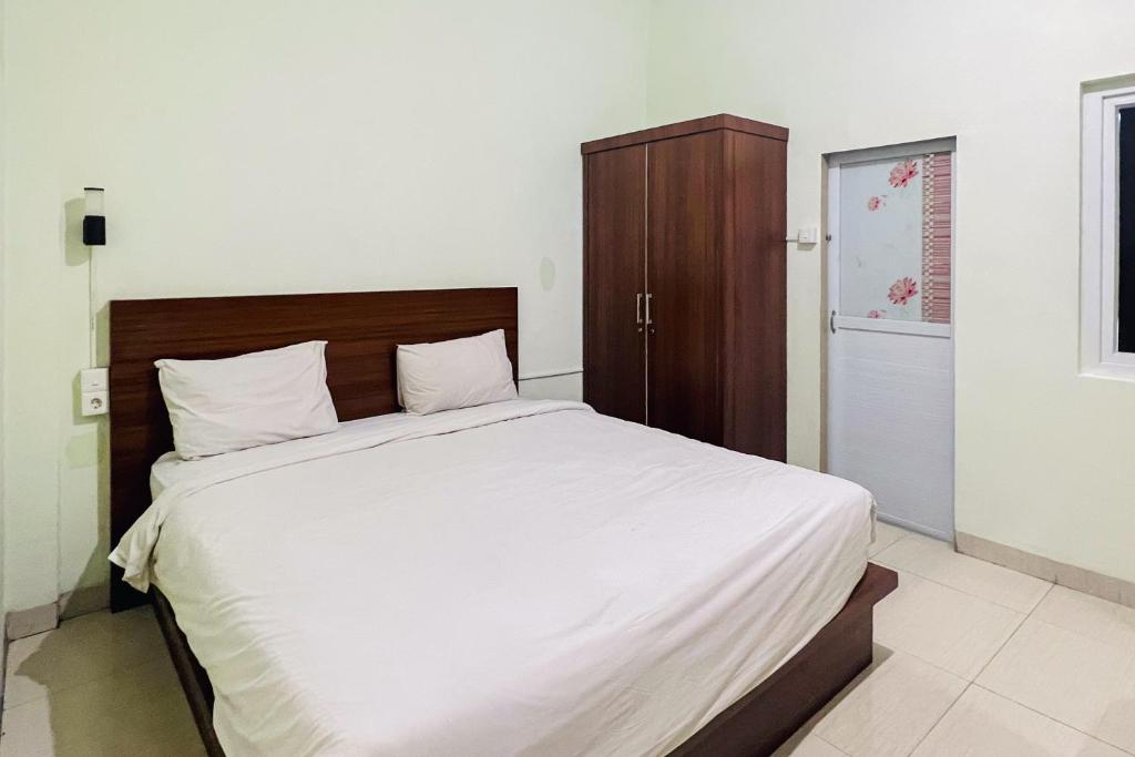 棉兰Teratai Residence Mitra RedDoorz的卧室配有一张白色大床和木制床头板