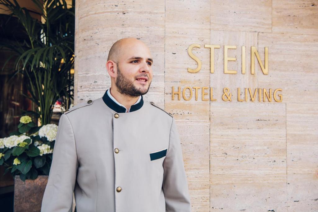 萨尔茨堡Hotel Stein - Adults Only的站在标志前身穿西装的人