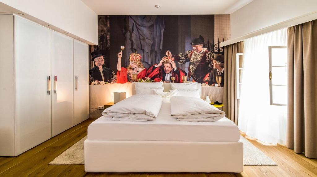 萨尔茨堡Small Luxury Hotel Goldgasse的墙上画作的白色床