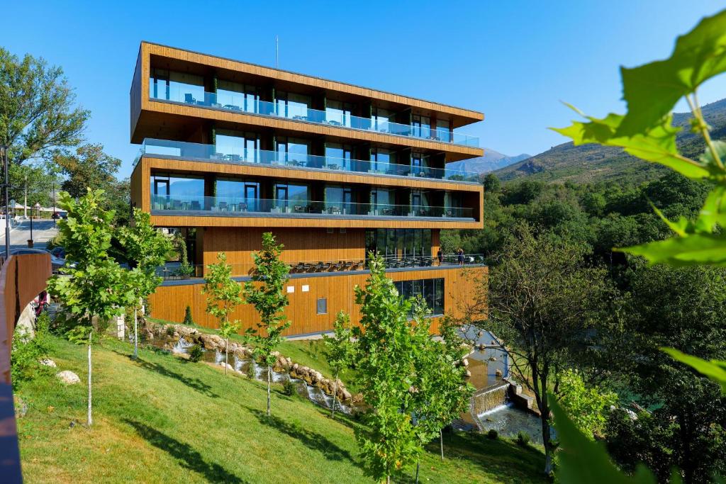 TepelenëHotel Uji Ftohte Tepelene的一座山丘上的建筑,前面有树木