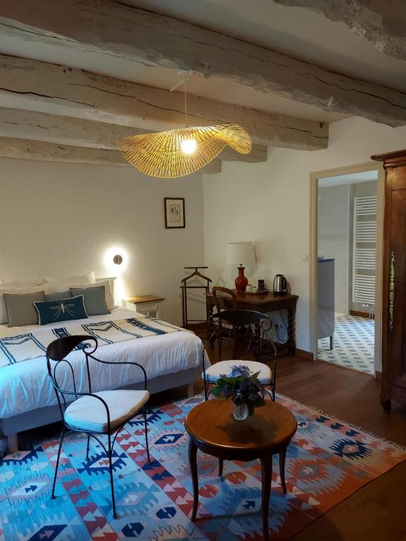 多尔德布列塔尼Manoir de l'Angélus的一间卧室配有一张床铺、椅子和一张桌子