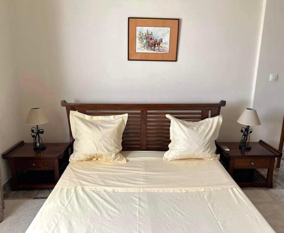 马哈赞加Mahajanga Residences的一间卧室配有一张带两张桌子和两盏灯的床。
