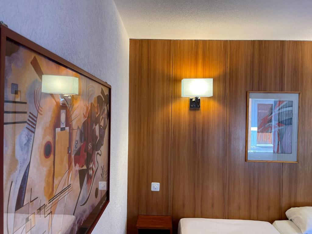 马蒂尼威尔Motel des Sports Martigny的一间卧室配有两盏灯,墙上挂着一幅画