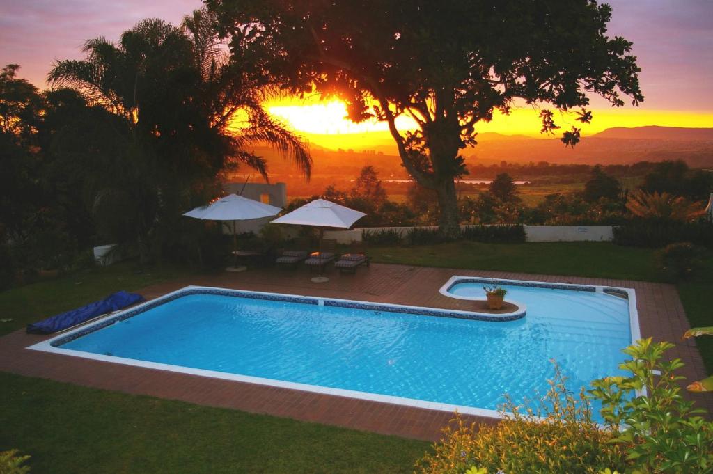 雾观Plumbago Guest House的一座享有日落美景的游泳池