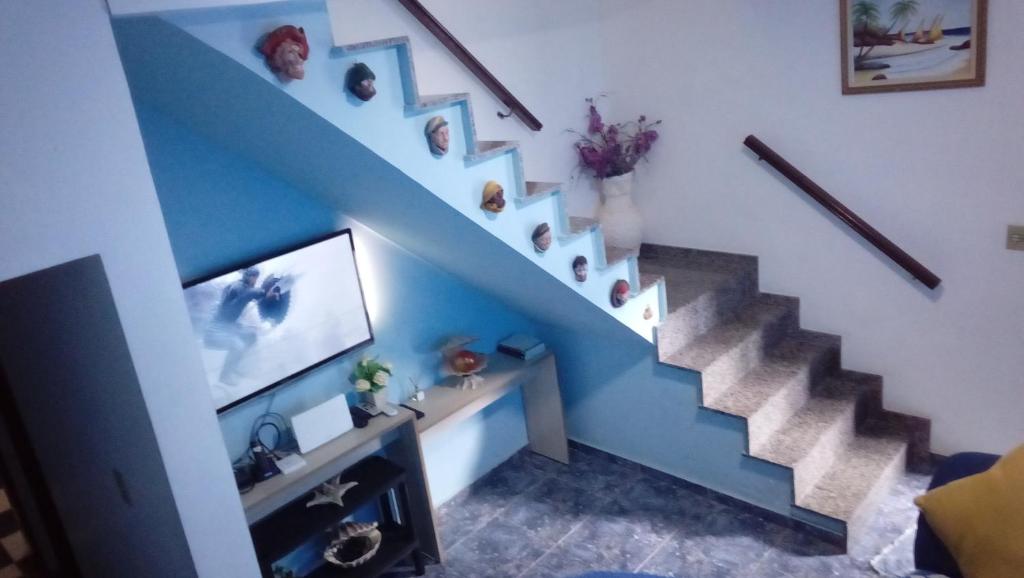 蒙加瓜Casa Mongagua的客厅设有蓝色楼梯和电视