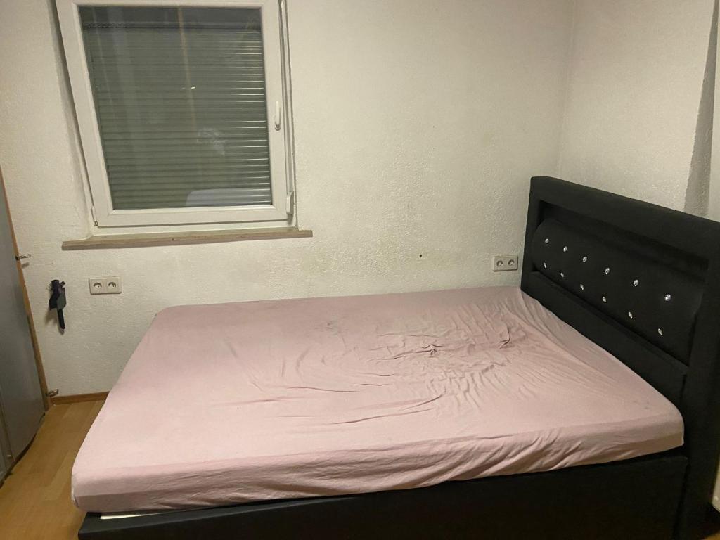 阿伦1 Zimmer mit Bad und Küche in Aalen的窗户客房内一张带粉红色床垫的床