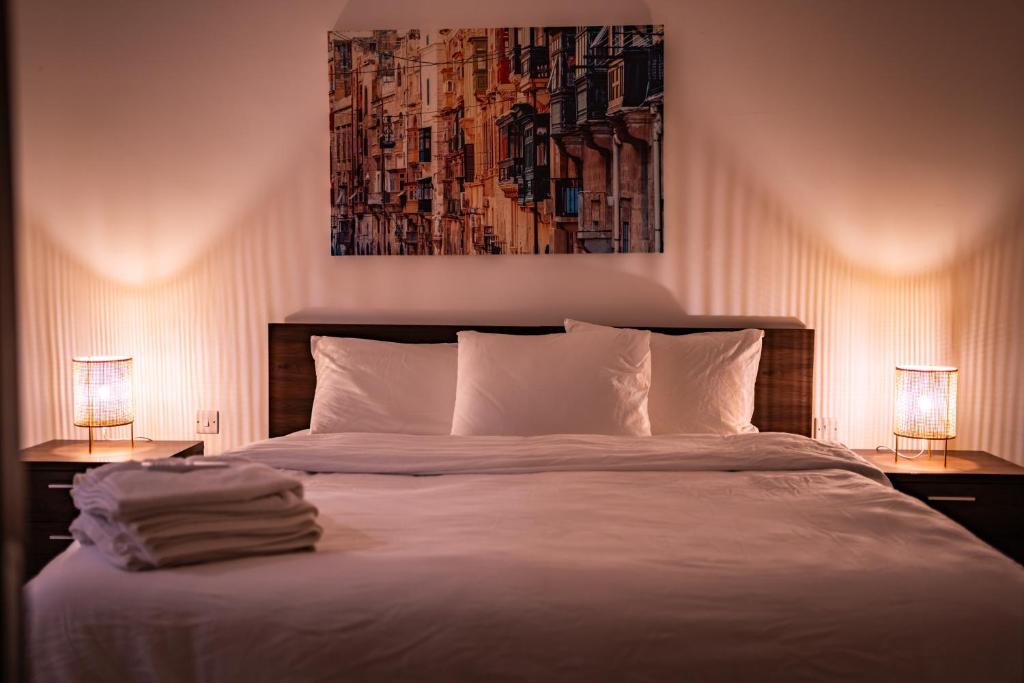 比尔基卡拉Designer 3 Bedroom / Bathroom Apartment in Swatar.的一间卧室配有一张带两盏灯和一幅画的床铺