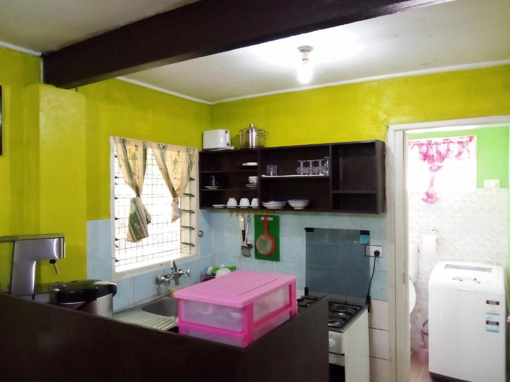 霍尼亚拉Island Home的厨房设有黄色的墙壁和粉红色的盒子