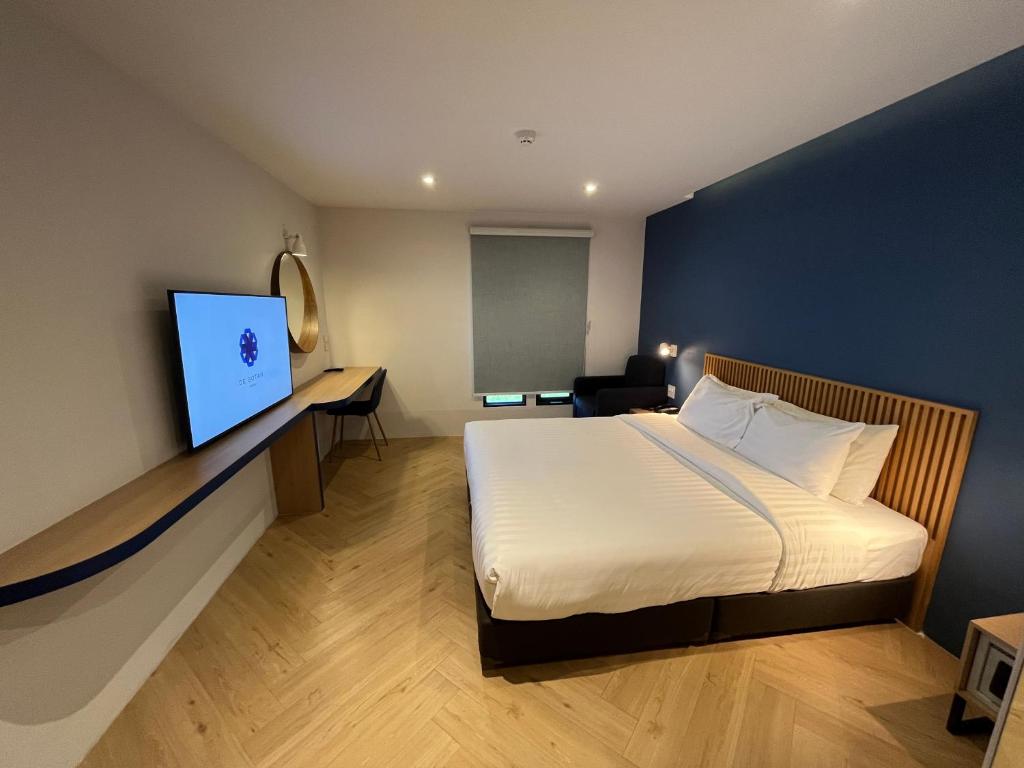 曼谷De Botan Bangna的配有一张床和一台平面电视的酒店客房