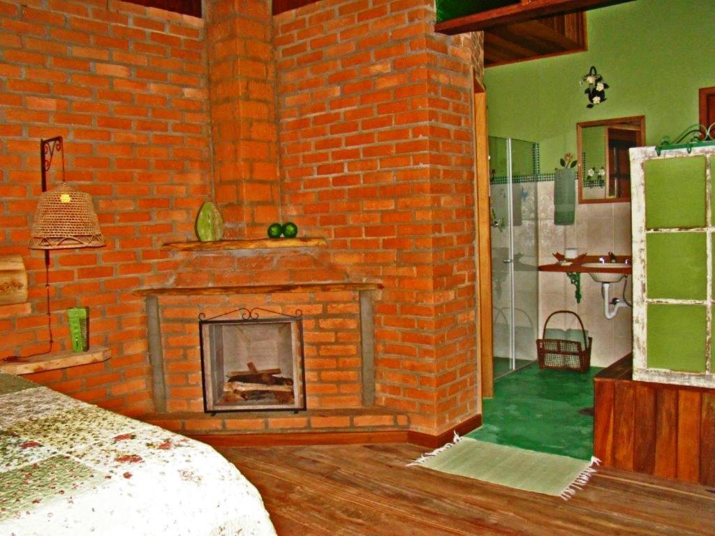 维奥康德马奥Chalé dos Gnomos的砖砌的客房设有壁炉和卧室。
