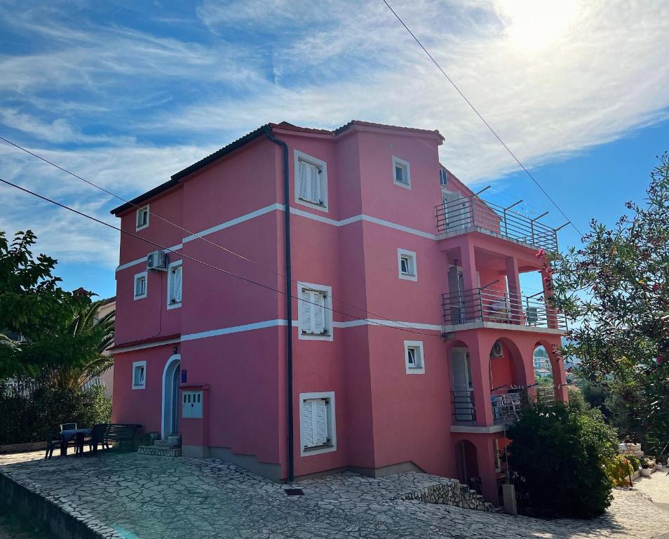 拉布Apartments Aleksandra的粉红色的建筑,有天空的背景