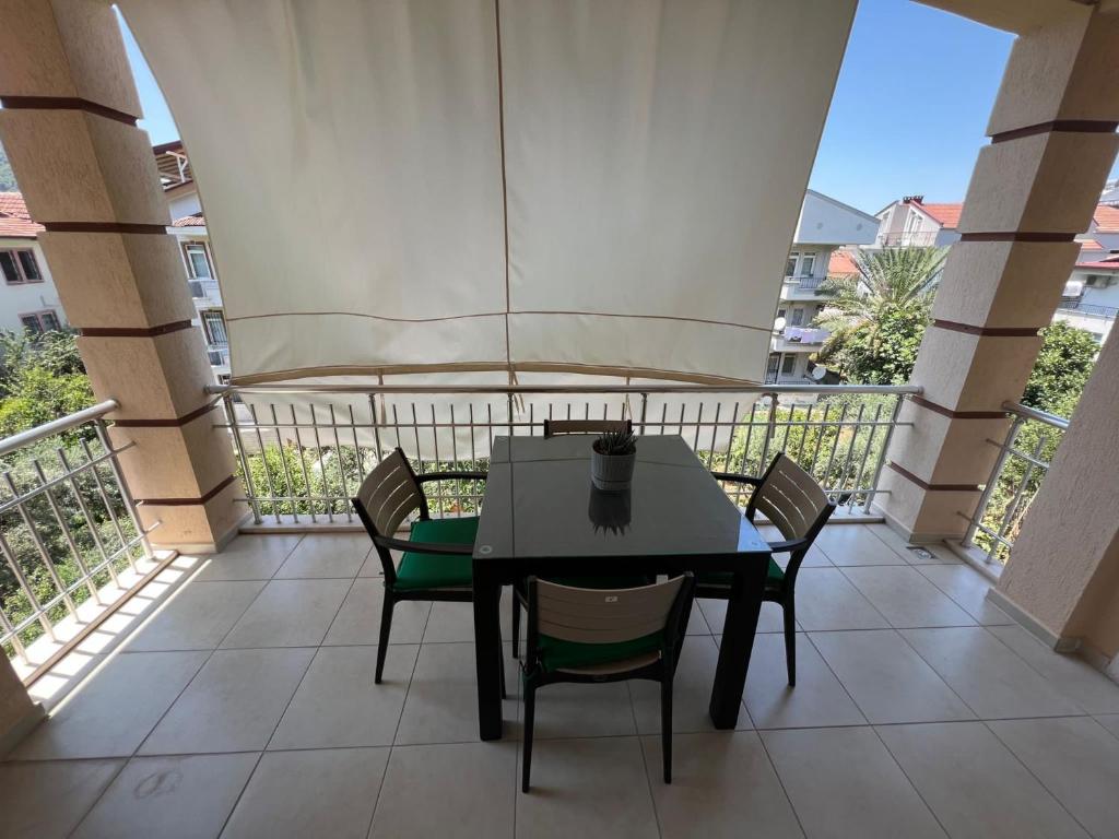 费特希耶Tanaydın Evleri的阳台配有桌椅和遮阳伞