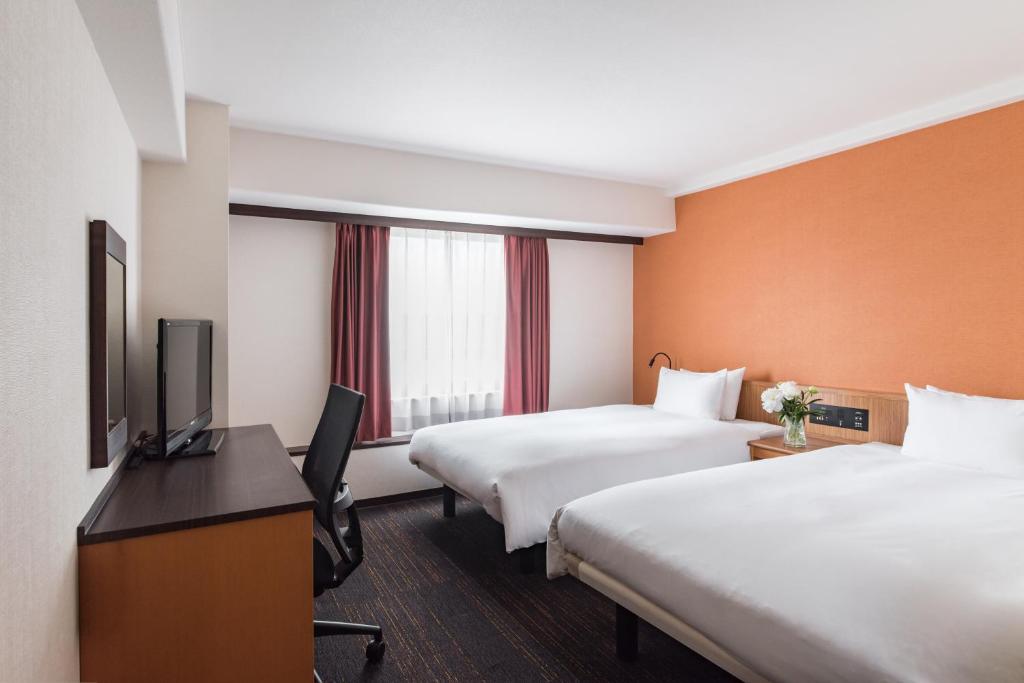 名古屋the b nagoya的酒店客房设有两张床和一台平面电视。