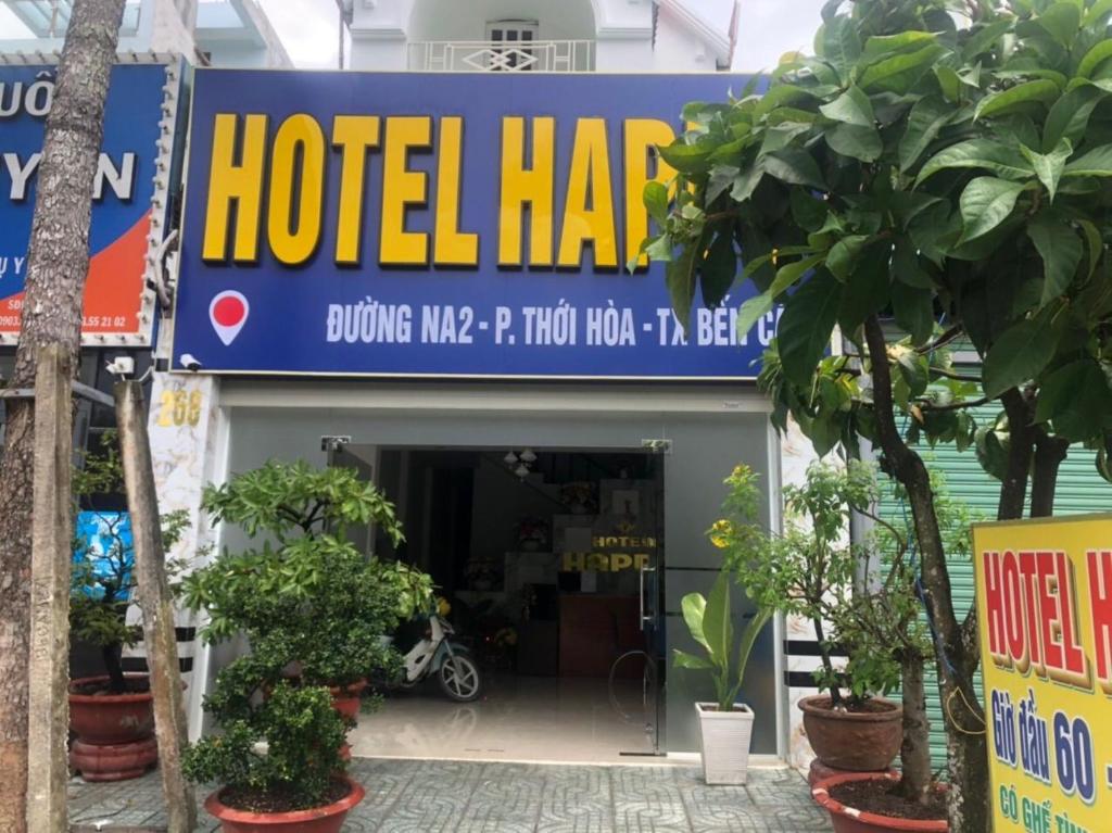 Bến CátHappy 1 Hotel Binh Duong的前面有植物的酒店庄园的标志