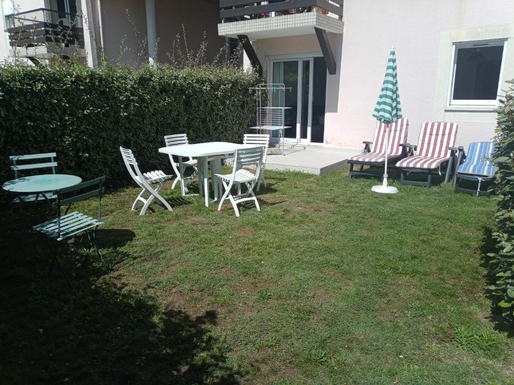 阿尔宗Appartement 2 pièces RDC jardin dans résidence avec piscine的庭院配有椅子和桌椅