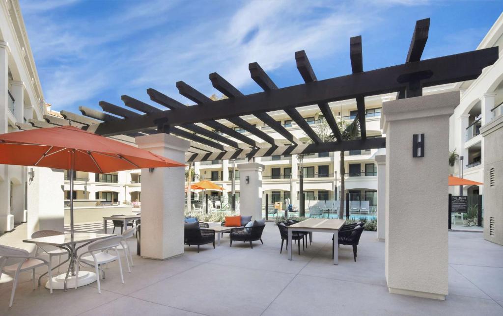 圣地亚哥美丽华圣地亚哥舒适套房酒店的一个带桌椅和遮阳伞的户外庭院。