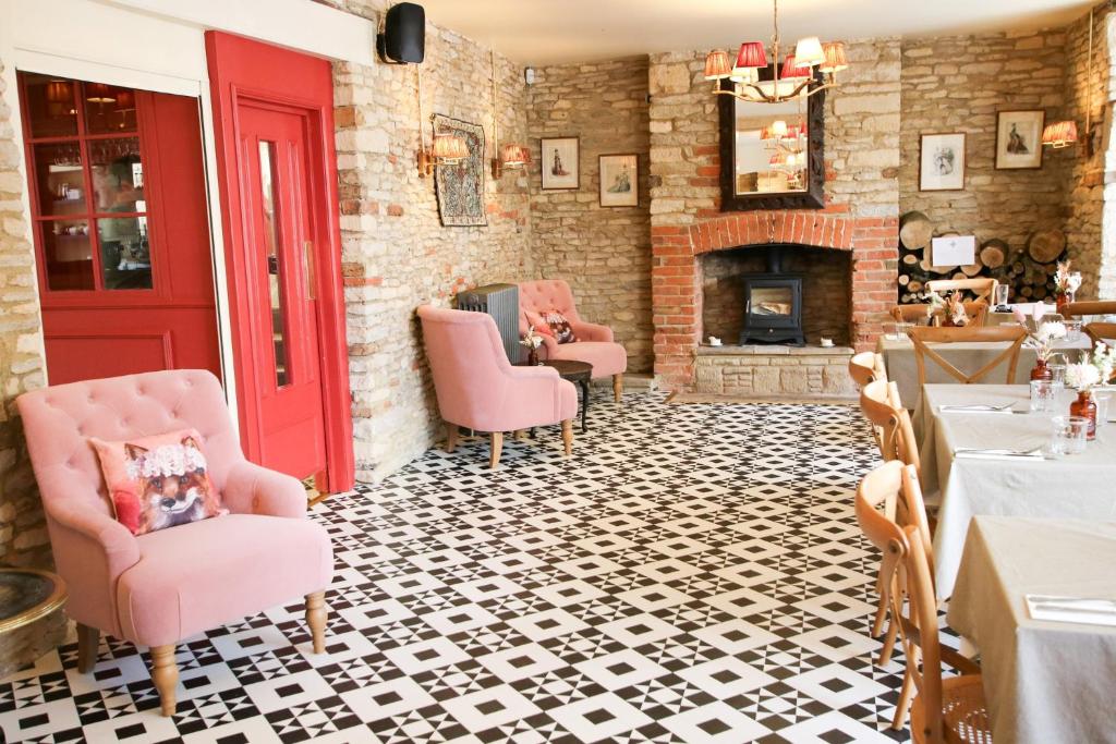 BamptonFleur de Lys Bampton的一间设有粉红色椅子和壁炉的客房