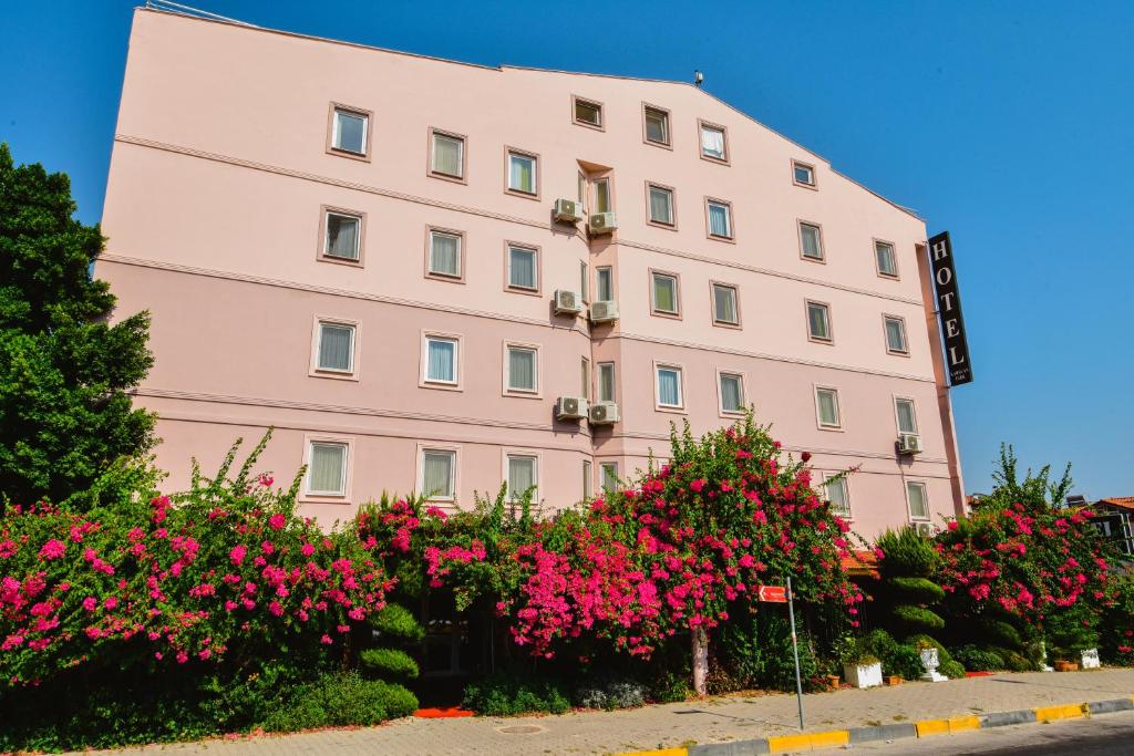达拉曼Karacan Park Hotel -Dalaman Airport的粉红色的建筑,前面有粉红色的花朵