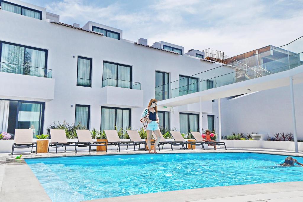 蓬塔德尔加达Pêro Teive Bay Apartments Hotel的站在一座建筑物前的游泳池旁的女人
