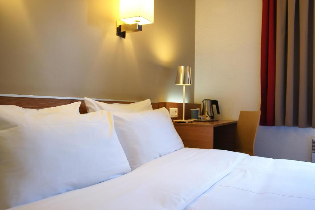勒布尔热基里亚德布杰中央世博园酒店的一间卧室配有一张带白色枕头的床和一张书桌