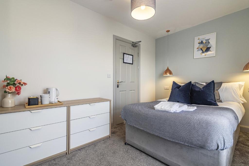 德比Stay @ Baker Street Derby的一间卧室配有一张带蓝色枕头的床和梳妆台