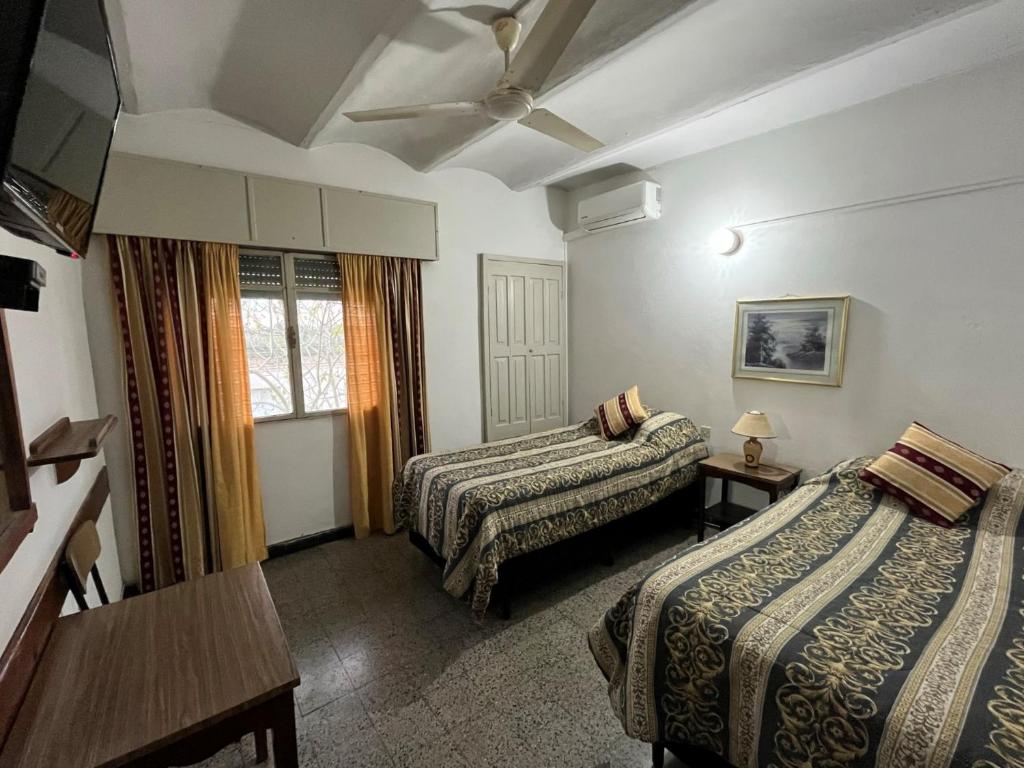 Rosario罗萨里奥酒店的酒店客房设有两张床和一张桌子。