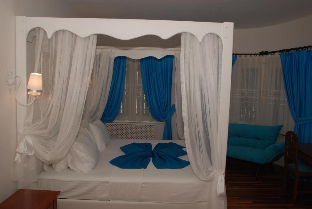 埃尔代克蓝色珍珠公园酒店的一间卧室配有白色的床和蓝色窗帘
