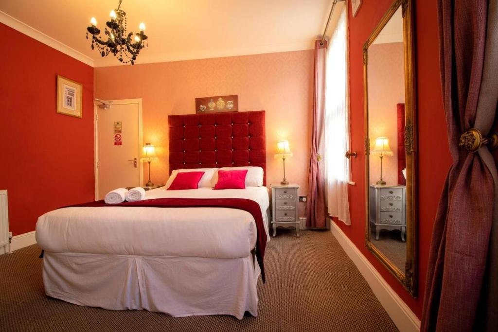 布莱克浦Hotel LUX (Rouge)的一间卧室配有一张大床、红色的墙壁和镜子