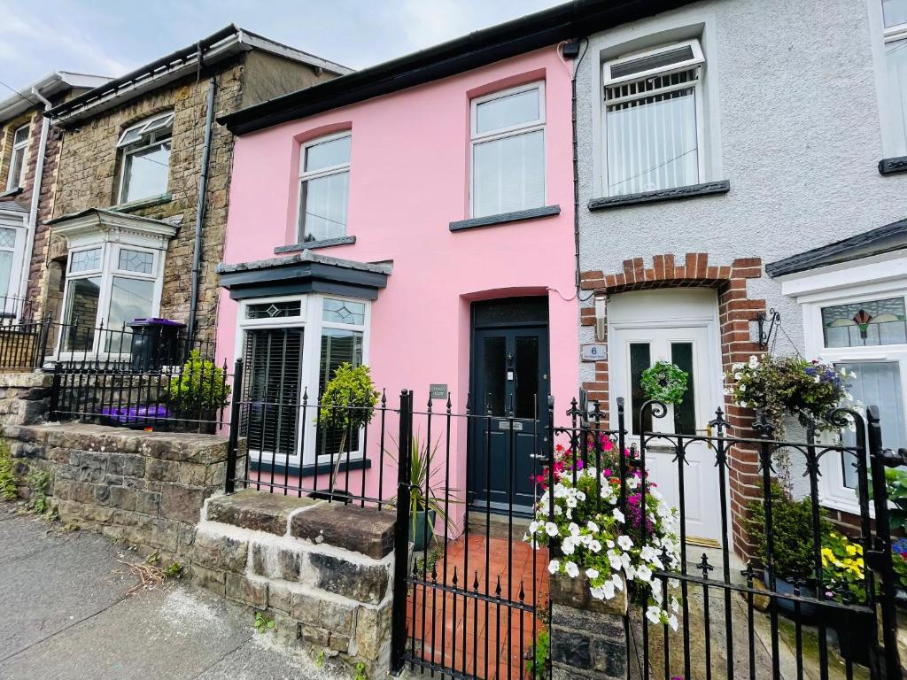 BlaenavonSTANLEY HOUSE 3 bed period house in Heritage Town - Brecon Beacons的粉红色的房子,有黑色的围栏和鲜花