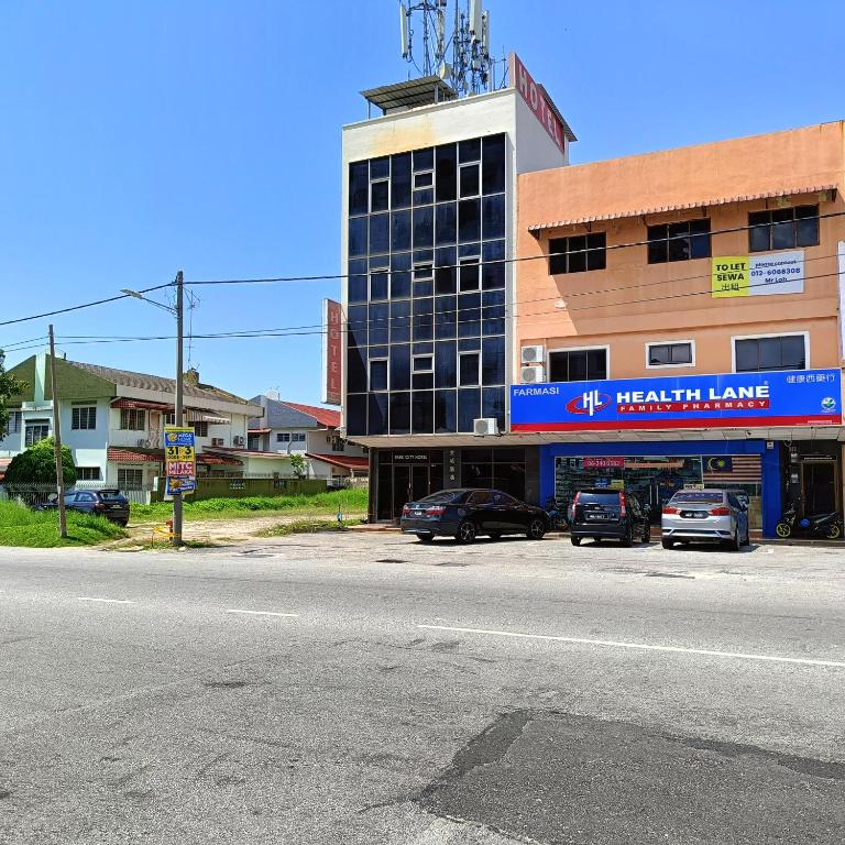 马六甲Park City Motel的一座大型建筑,前面有汽车停放