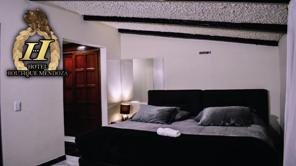 波哥大Hotel Boutique Mendoza - Cerca Aeropuerto El Dorado的卧室配有一张黑色床,墙上有标志