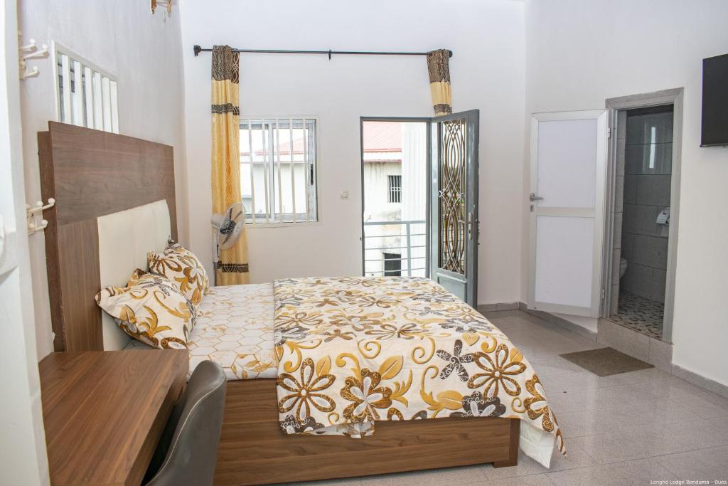 BueaLongho Lodge Bundoma - Buea的一间卧室配有一张床、一张桌子和一个窗户。