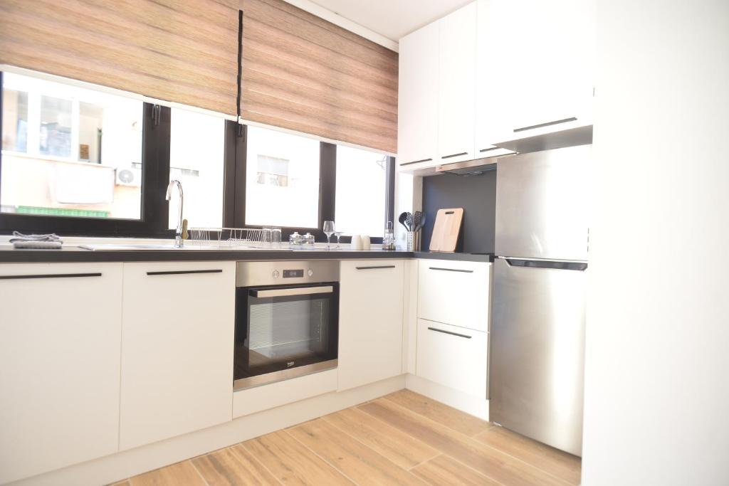 地拉那Tirana Central Apartments的厨房配有白色橱柜和不锈钢冰箱