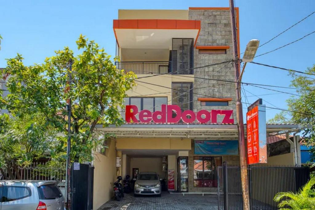 泗水RedDoorz Syariah near Airlangga University Campus B的一间红色的书店,前面有汽车停放