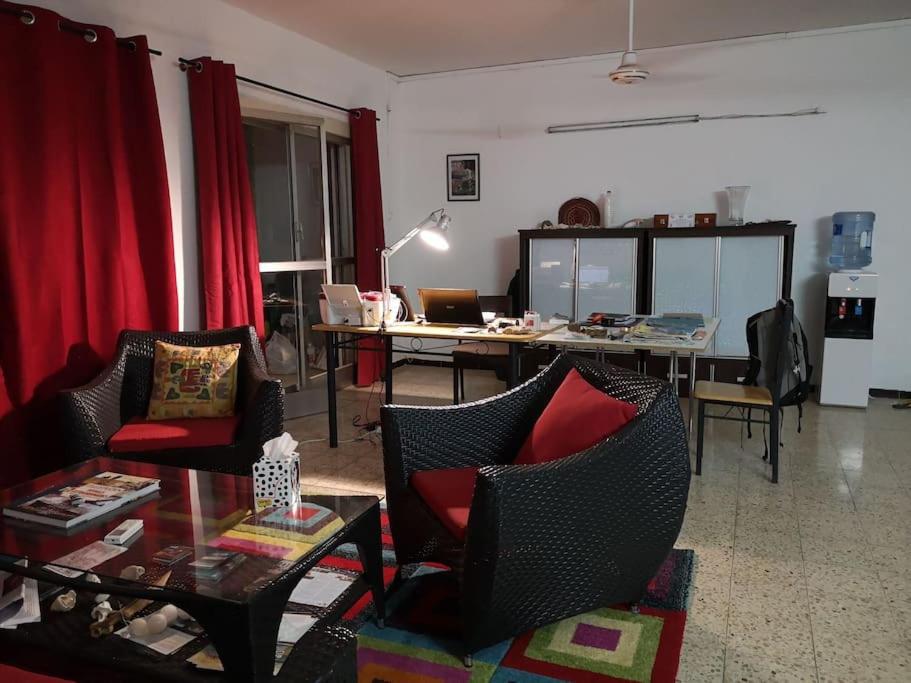 吉布提Appartement meublé au Héron的客厅配有红色窗帘和桌椅