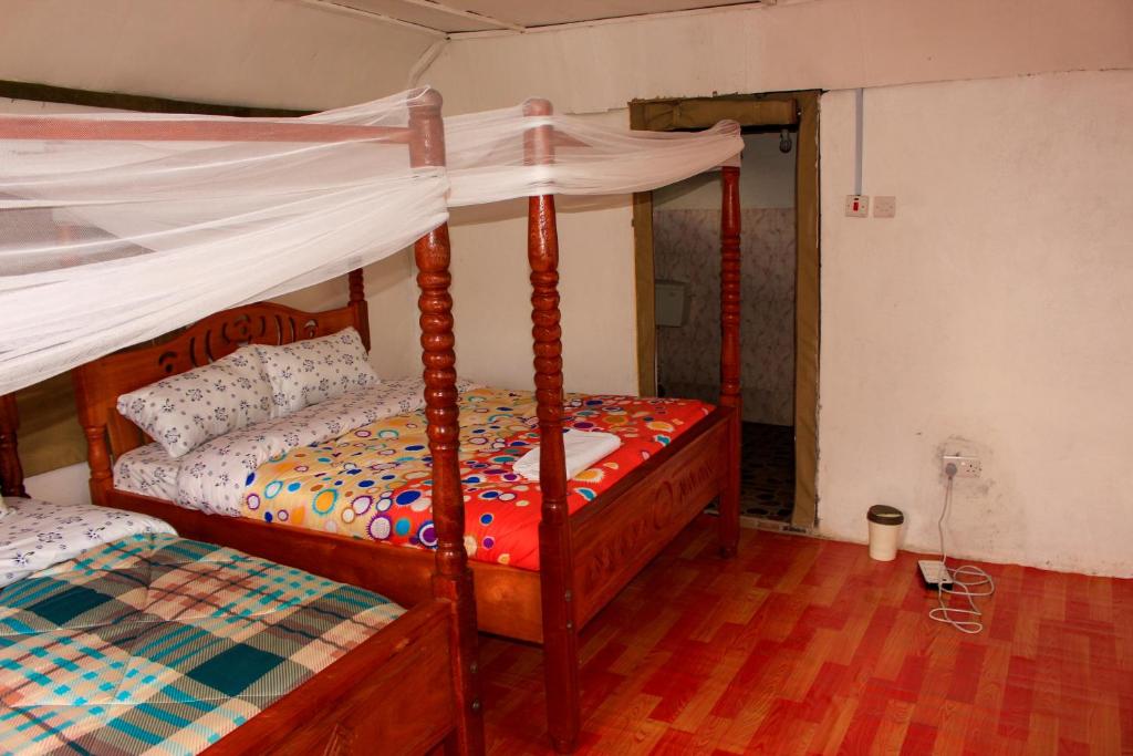 凯科罗克Mara Forest camp的一间卧室配有两张带天蓬的床