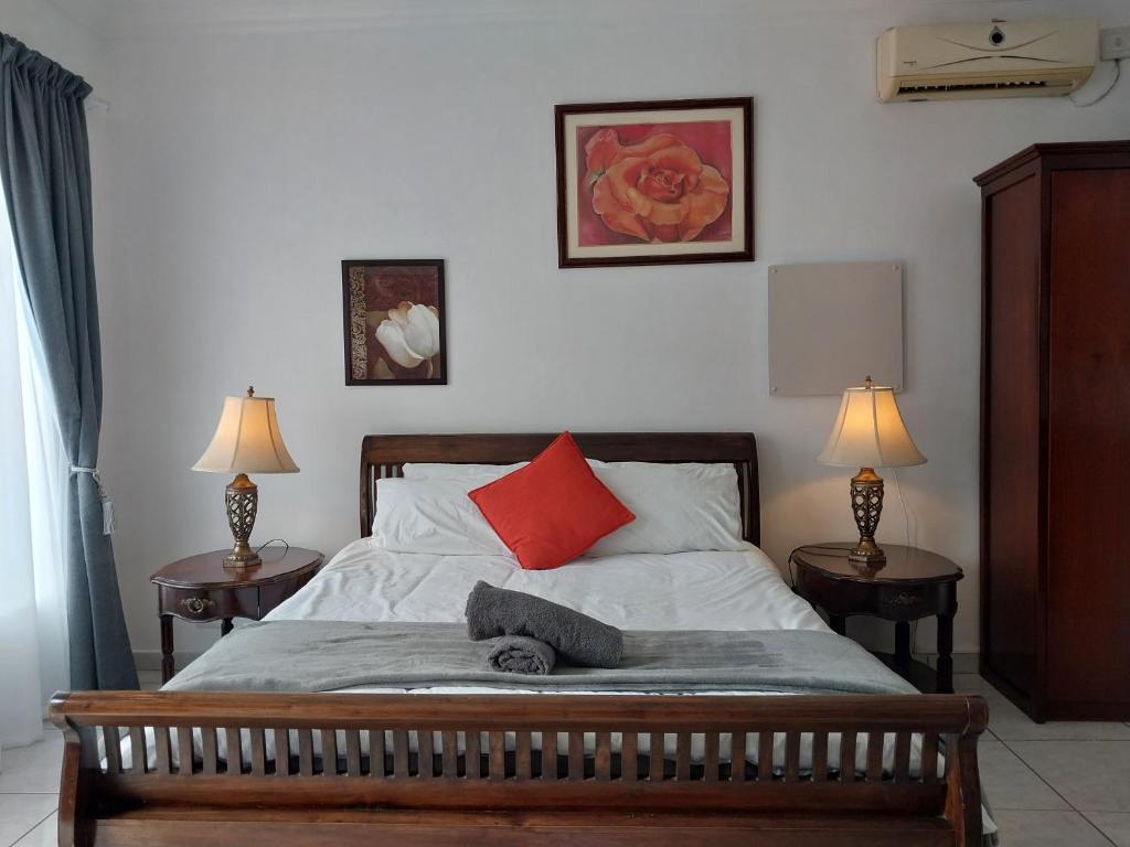 比勒陀利亚The Freshwater Pearl的一间卧室配有一张带红色枕头和两盏灯的床