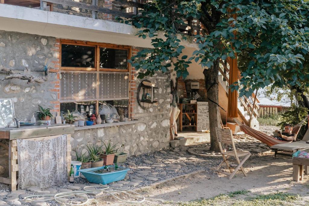 地拉那The house in the village的石头建筑,有长凳和树