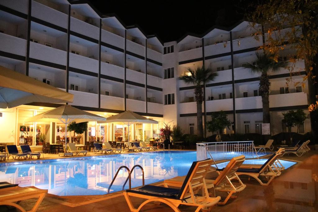 锡德SİDE SPRİNG HOTEL的夜间带椅子和遮阳伞的酒店游泳池