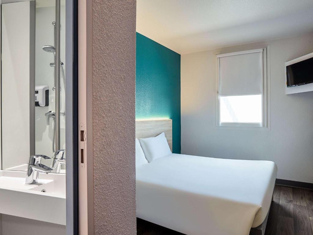 CourcouronneshotelF1 Evry A6的浴室设有白色的床和水槽。