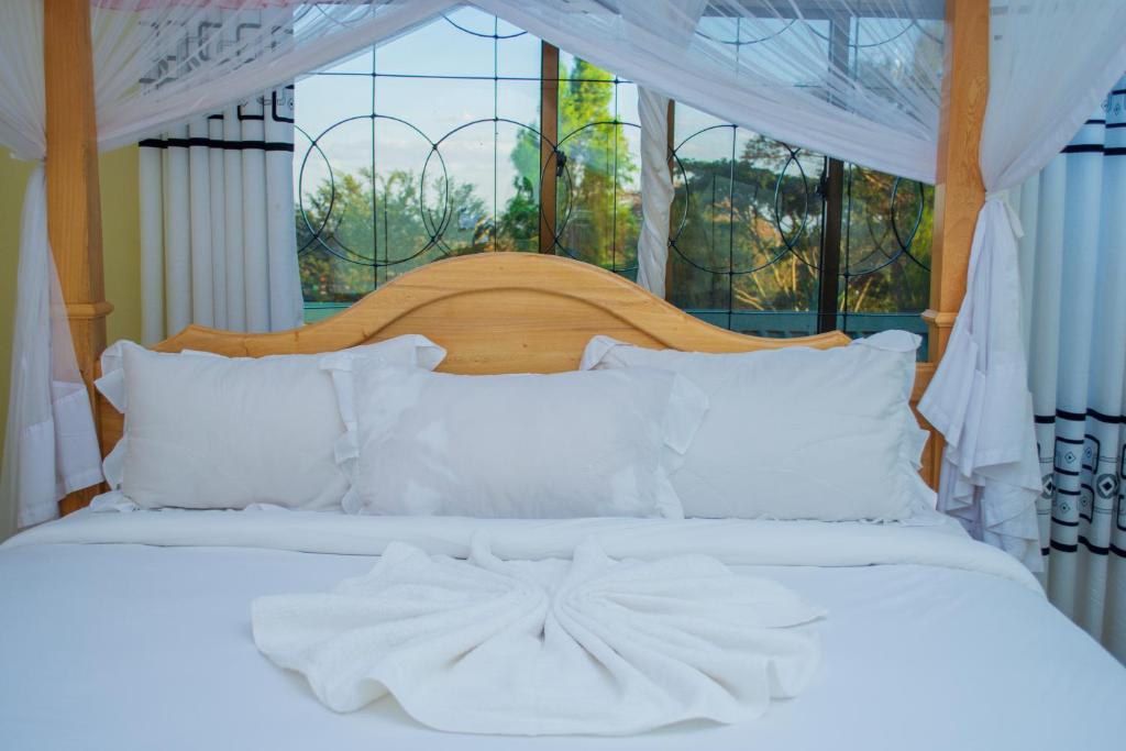 育空河Mzunguu Safari Lodge的一张带白色床单和枕头的床,位于窗户前