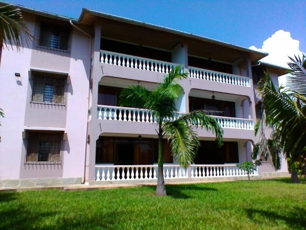 KwaleGalu Gardens Diani Beach ,Coastal Apartments by Nest & Nomad的前面有棕榈树的建筑