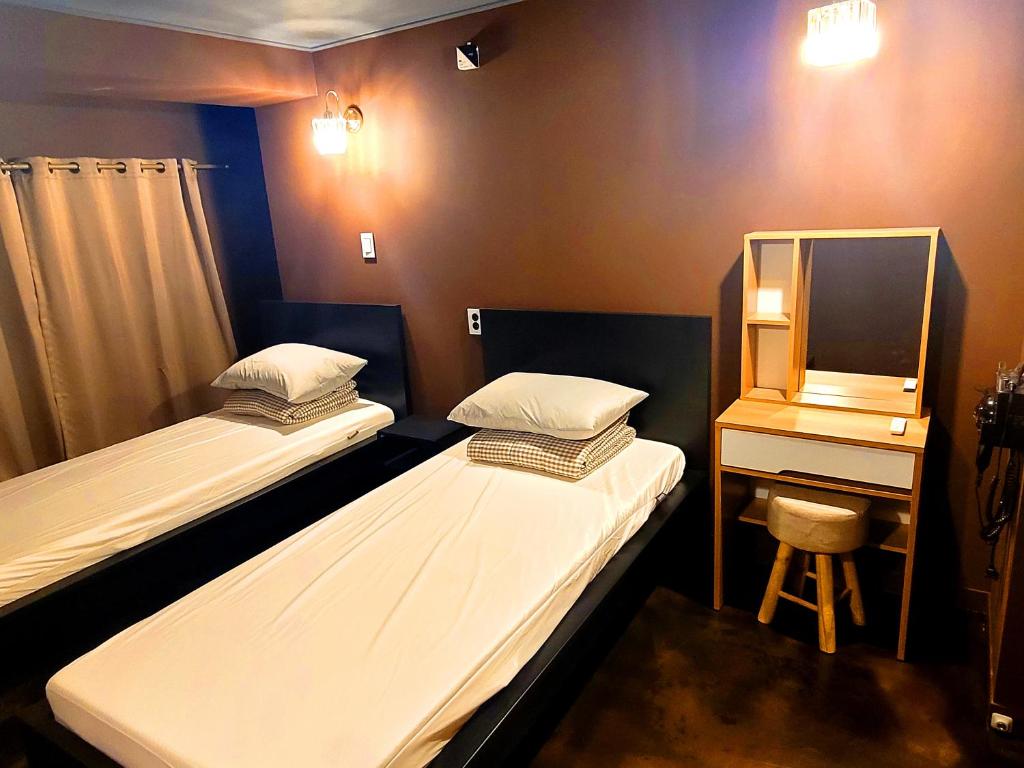 首尔Good Guesthouse #2的配有两张床铺的客房配有一张桌子和一面镜子
