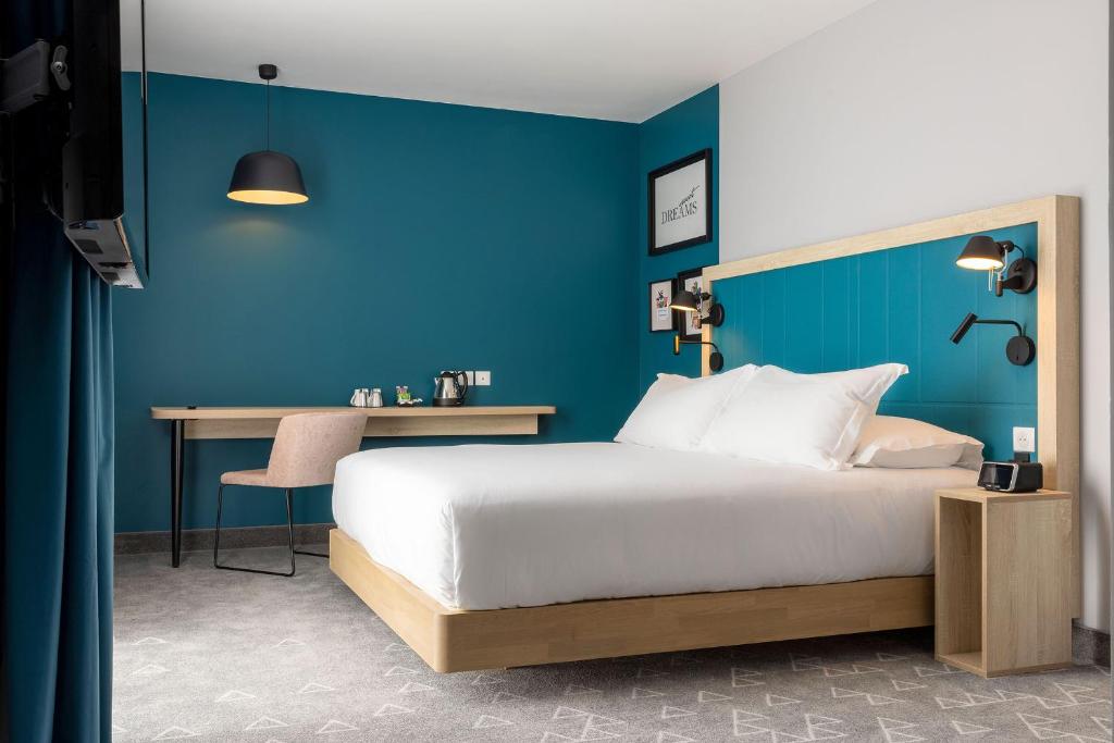 图尔Hampton by Hilton Tours Centre, France的一间设有蓝色墙壁、一张床和一张书桌的卧室