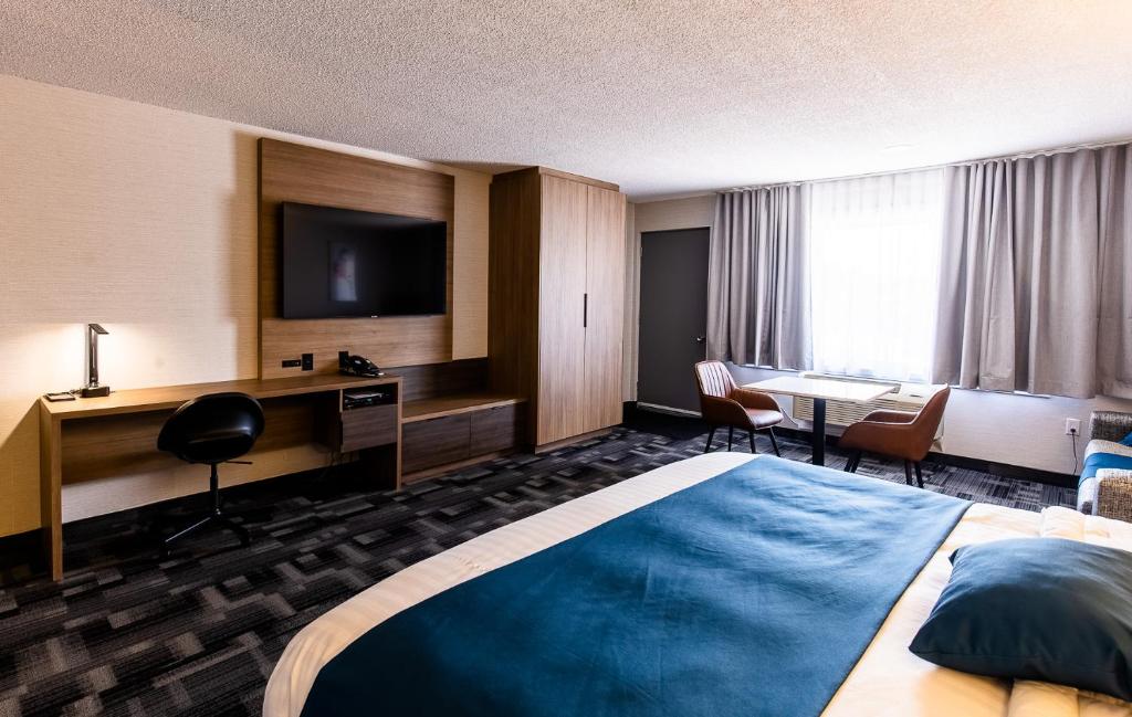 蒙洛里耶Auberge L'Étape的酒店客房设有一张床、一张书桌和一台电视机。